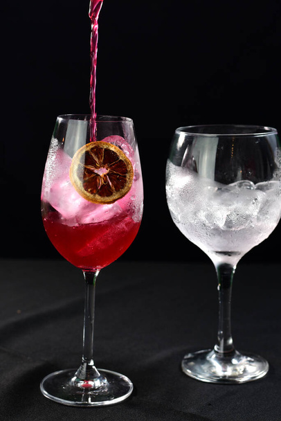 verfrissende alcoholische drank met fruit, gekoelde wodka en gin, citroenschil geserveerd in glazen tumbler - Foto, afbeelding