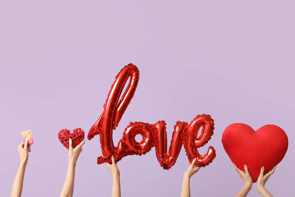 Mujeres con tarjeta de crédito y corazones sobre fondo lila. Celebración de San Valentín - Foto, imagen