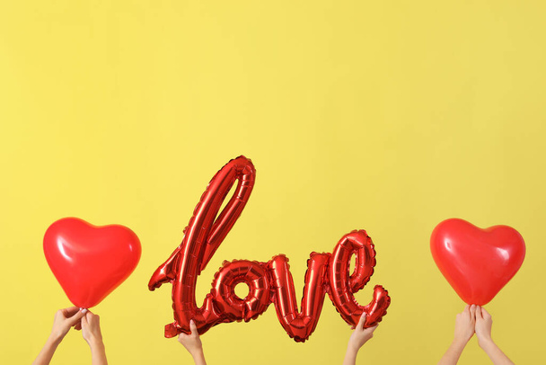 Femmes avec mot AMOUR et ballons sur fond jaune. Fête de la Saint-Valentin - Photo, image