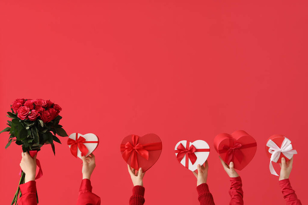 Ženské ruce drží dárkové krabice a kytice krásných růží na červeném pozadí. Valentýnská oslava - Fotografie, Obrázek
