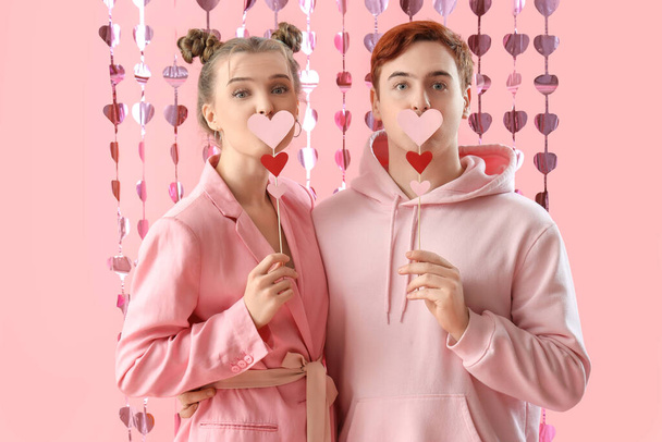 Casal jovem com corações no fundo rosa. Celebração do Dia dos Namorados - Foto, Imagem