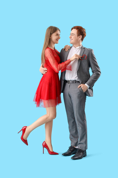 Young couple with heart in pocket on blue background. Valentine's Day celebration - Photo, Image