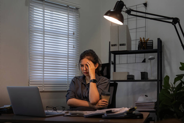 Femme d'affaires asiatique au bureau, fatiguée ou fatiguée tout en travaillant tard dans la nuit sur ordinateur portable. Burnout, migraine et femme avec dépression, anxiété ou brouillard cérébral, stress et délai. - Photo, image