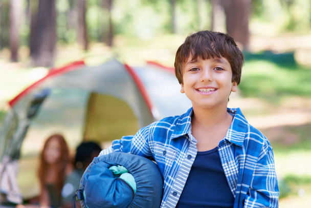 Slaapzak, camping of portret van een gelukkig kind in het bos voor avontuur of vakantie in het park. Ontspan, start of jongen met een glimlach in de natuur, tuin of bos klaar voor leuke wandelingen, reizen of wellness. - Foto, afbeelding