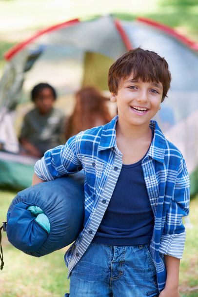 Sleeping bag, camping or portrait of happy boy in forest on adventure or holiday vacation in nature. Relax, start or kid with smile in park, garden or woods ready for fun hiking, travel or wellness. - Photo, Image
