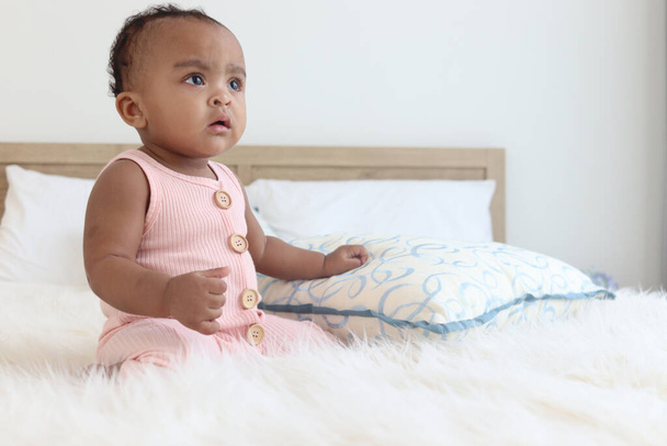 Happy African mignon bébé bébé fille bébé assis sur lit blanc dans la chambre à coucher. Portrait d'adorable petit enfant à la maison, visage heureux de l'enfant, enfance  - Photo, image