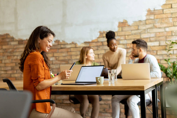 Mooie zakenvrouw werken op laptop met haar jonge multi-etnische startup team werken in het moderne kantoor - Foto, afbeelding
