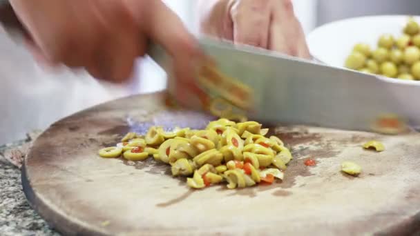 Σεφ χέρι σε φέτες πράσινες ελιές σε Cutting Board - Πλάνα, βίντεο