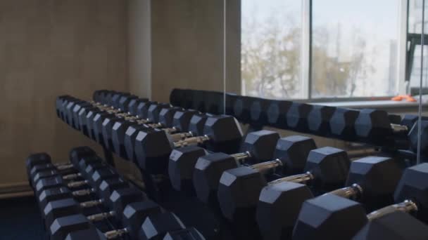 Langsame Aufnahme eines nicht wiederzuerkennenden männlichen Athleten, der beim Training im Fitnesscenter Hanteln aus der Reihe nimmt - Filmmaterial, Video