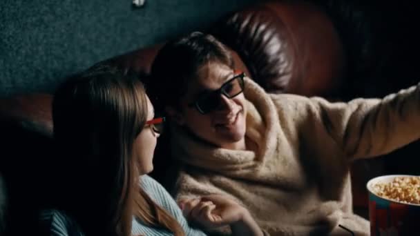 Pariskunta rakastunut Mies ja tyttö syövät popcornia ja katsovat elokuvaa 3D-laseilla. Elokuvateatterin konsepti - Materiaali, video