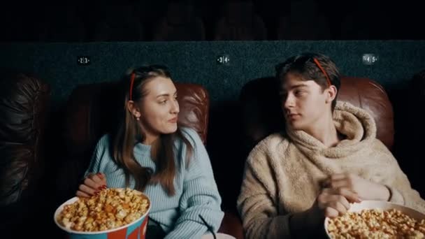 Пара влюбленных парень и девушка едят попкорн и смотрят фильм в кинотеатре, используя 3D очки. Концепция кинопоказа в кино - Кадры, видео