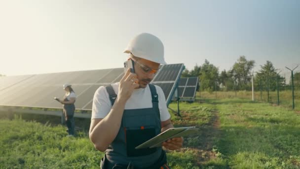 An energy specialist uses information read from digital tablets to check the efficiency of solar panel designs. Jobs in green energy. Technologies. Innovation. High quality 4K footage - Footage, Video