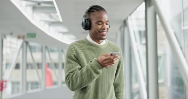 Music, happy and business with black man and phone for streaming, social media and radio. Podcast, technology and headphones with male employee dancing in office building for audio and mobile app. - Footage, Video