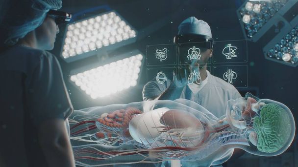 Diverse surgeons in AR headsets work in operating room. African American specialist uses virtual holographic display with 3D animation of human skeleton and organs. Technology of AI-assisted surgery. - Photo, Image