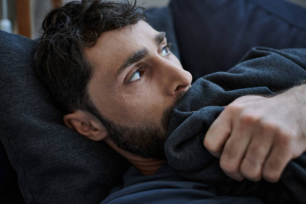 depressiver bärtiger Mann in lässigem Outfit liegt während des Zusammenbruchs auf Sofa, Bewusstsein für psychische Gesundheit - Foto, Bild