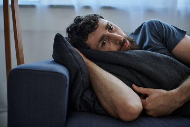 depresivní vousatý muž v ležícím oblečení na pohovce během zhroucení, duševní zdraví vědomí - Fotografie, Obrázek