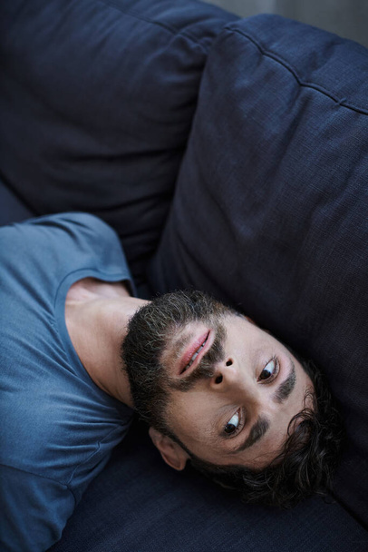zdesperowany mężczyzna w luźnej koszuli leżący na kanapie podczas epizodu depresji, zdrowie psychiczne - Zdjęcie, obraz