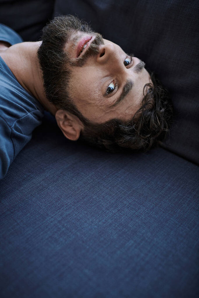 zoufalý depresivní muž v neformální tričko ležící na pohovce během depresivní epizody, duševní zdraví - Fotografie, Obrázek