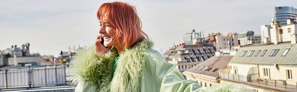 veselá žena ve stylovém neformálním oblečení mluví na mobilním telefonu na střešní terase ve Vídni, banner - Fotografie, Obrázek