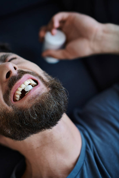 homem deprimido emocional com barba tomando pílulas durante episódio depressivo, consciência de saúde mental - Foto, Imagem