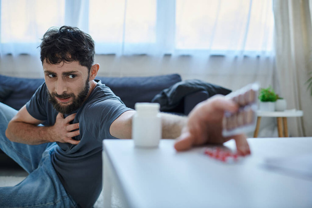 zaměření na úzkostlivý vousatý muž s depresivní epizodou sahající k jeho rozmazané pilulky, duševní zdraví - Fotografie, Obrázek
