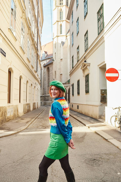 cheerful woman in beret and stylish clothes looking at camera on city street in Vienna, Austria - Photo, Image