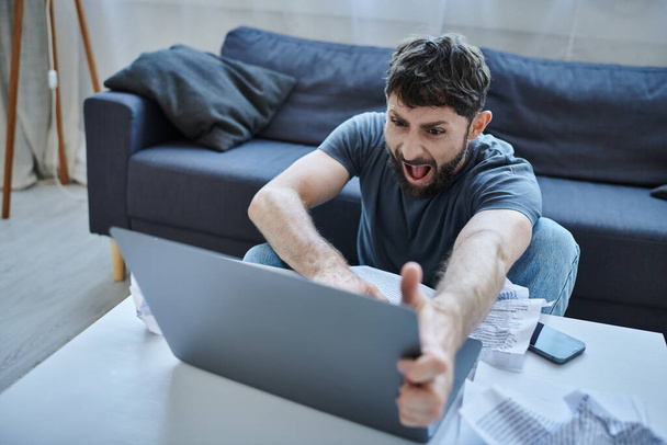 депрессивный человек в повседневной одежде кричит на свой ноутбук во время срыва, психического здоровья осведомленности - Фото, изображение