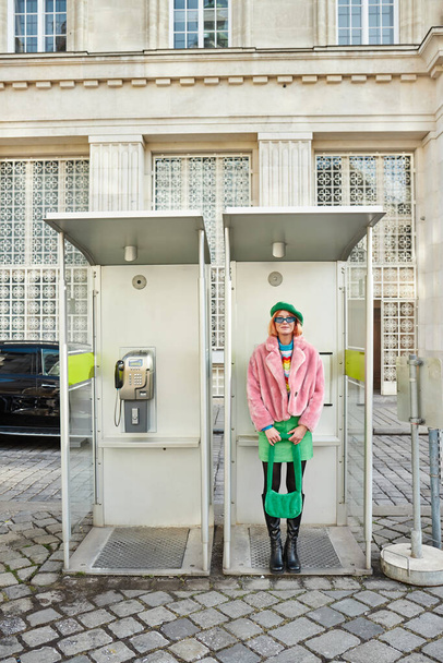 щаслива жінка в модному повсякденному вбранні позує в телефонній будці на вулиці у Відні, Австрія - Фото, зображення