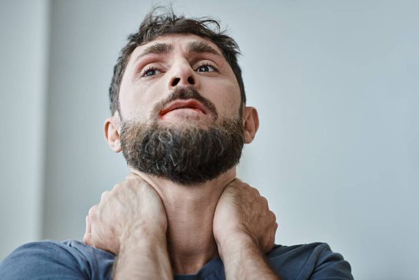 niespokojny sfrustrowany mężczyzna w luźnej koszuli gryzie się w usta aż do krwi podczas załamania, zdrowie psychiczne - Zdjęcie, obraz