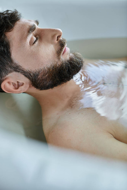 депрессивный травмированный человек с бородой, лежащий в ванне во время поломки, психическое здоровье осведомленности - Фото, изображение