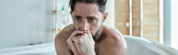 chory mężczyzna siedzi w wannie z dłońmi blisko twarzy podczas załamania, świadomość zdrowia psychicznego, baner - Zdjęcie, obraz