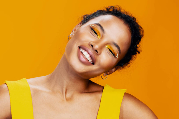 Μόδα γυναίκα αφρικάνικη αισθητική ομορφιά πολύχρωμο χώρο αντίγραφο μοντέλο κίτρινο δημιουργικό make-up κοσμετολογία όμορφο ροζ έθνικ πρόσωπο πορτρέτο δέρμα στυλ χαμόγελο μαύρο στούντιο - Φωτογραφία, εικόνα