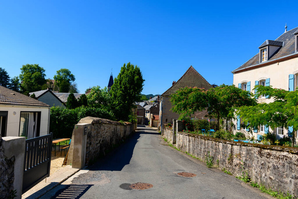 Dieses Landschaftsbild wurde im Sommer in Europa, in Frankreich, in Burgund, in Nievre, in Larochemillay, in Richtung Chateau Chinon aufgenommen. Wir sehen das alte Dorf in der grünen Landschaft, unter der Sonne. - Foto, Bild