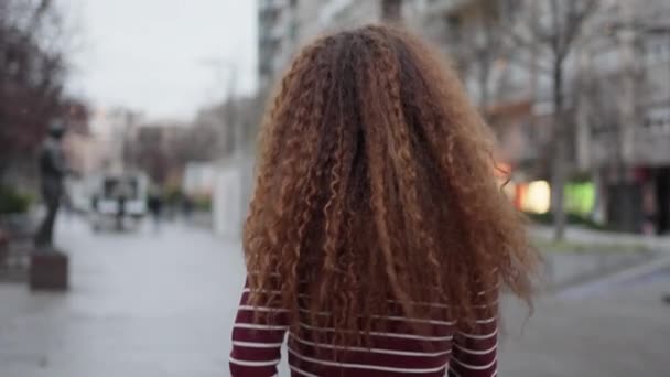 Міське хвилювання: впевнена молода жінка з афро волоссям прогулюючись міськими вулицями - Кадри, відео