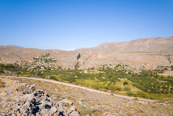 Dieses Landschaftsbild wurde in Europa, in Griechenland, auf Kreta, in Kato Zakros, am Mittelmeer, im Sommer aufgenommen. Wir sehen die grüne Landschaft am Fuße der felsigen Berge, unter der Sonne. - Foto, Bild
