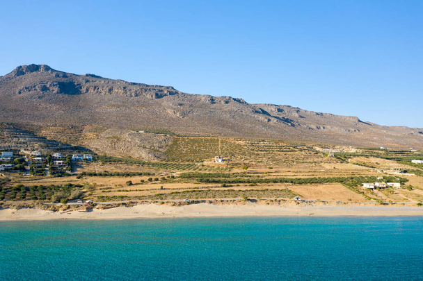 Questa foto di paesaggio è stata scattata, in Europa, in Grecia, a Creta, verso Zakros, Sulla riva del Mar Mediterraneo, in estate. Vediamo la spiaggia di sabbia fine di Ambelou ai piedi delle montagne, sotto il sole. - Foto, immagini