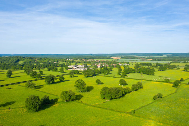 Esta foto de paisaje fue tomada en Europa, en Francia, en Borgoña, en Nievre, en Cuncy les Varzy, hacia Clamecy, en primavera. Vemos un pueblo francés en el verde campo, bajo el sol. - Foto, Imagen