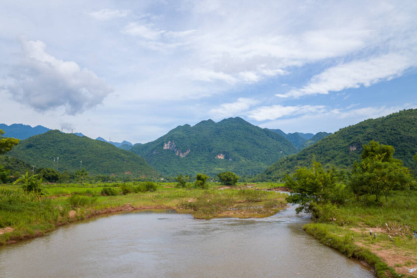 Bu manzara fotoğrafı Asya 'da, Vietnam' da Tonkin 'de, Hanoi' de, Mai Chau 'da, yazın çekildi. Yeşil pirinç tarlalarının ve dağların ortasında, güneşin altında bir nehir görüyoruz.. - Fotoğraf, Görsel