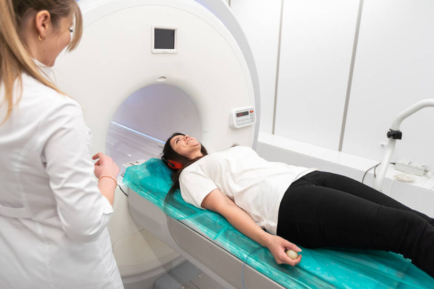 Modern hastane laboratuvarında bir hastaya tıbbi tomografi ya da MRI taraması yapın. Radyografi bölümünün içi. Beyaz odada teknolojik olarak gelişmiş ekipmanlar var. Manyetik rezonans tanılama makinesi. - Fotoğraf, Görsel