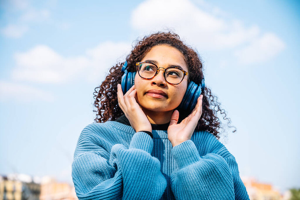 Bir kadın, lüks bir şehir parkında müzik dinlemekten zevk alır.. - Fotoğraf, Görsel