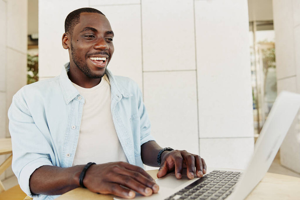 Человек человек ноутбук бизнес с использованием рабочего образа жизни компьютерный бизнесмен сидит африканский офис счастливый мужчина технологии Интернет взрослый молодой черный - Фото, изображение