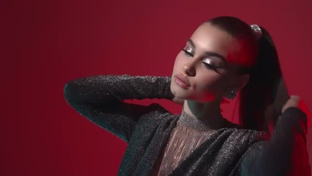 A young seductive fashion model girl with bright evening makeup and stylish hairstyle shows off jewelry with precious stones, poses and looks at the camera in the light of red lanterns. - Footage, Video