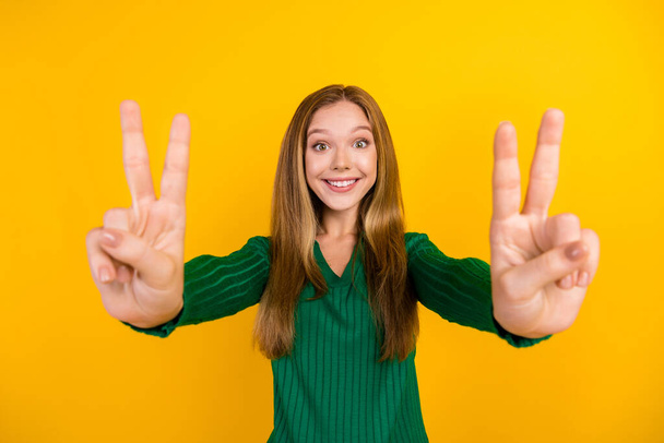 Photo of satisfied glad young lady beaming smile arms fingers demonstrate v-sign isolated on yellow color background. - Foto, Imagem