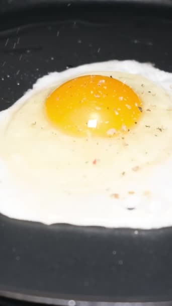Κοντινό πλάνο ενός αυγού κοτόπουλου που τηγανίζεται σε ένα καυτό τηγάνι. Αργή κίνηση. Κάθετη βίντεο. - Πλάνα, βίντεο