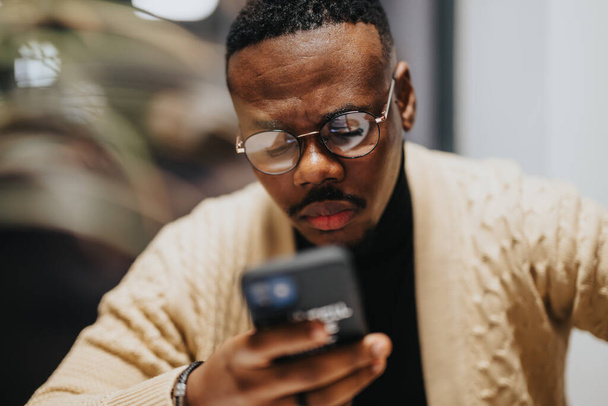 Während einer Pause blickt ein Mann auf sein Handy und bleibt bei der Arbeit in Verbindung. - Foto, Bild