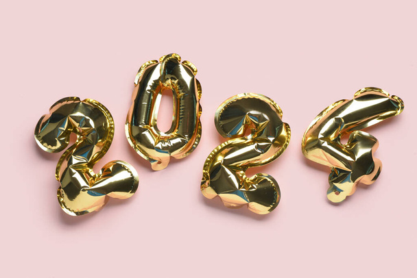 Gouden folie ballonnen nummer 2024 op roze achtergrond. Nieuwjaarsconcept. - Foto, afbeelding