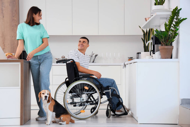 Νεαρός σε αναπηρική καρέκλα και η σύζυγός του με το σκυλί Beagle στο σπίτι - Φωτογραφία, εικόνα