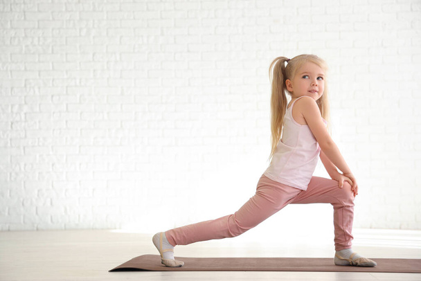 Pieni tyttö tekee voimistelu matto kuntosalilla - Valokuva, kuva