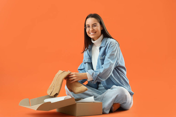Vendeur femelle avec bottes en boîte sur fond orange - Photo, image