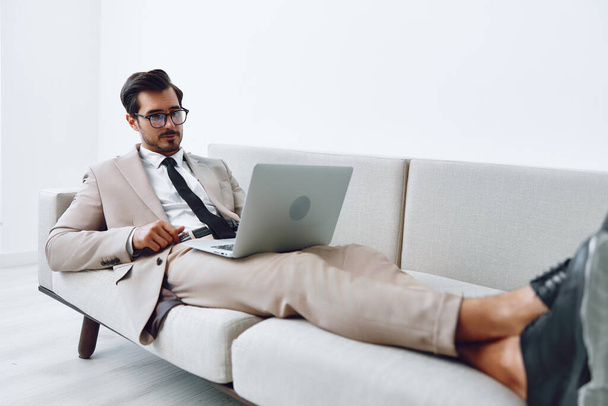 Коммуникационный человек онлайн ноутбук видео сидя глядя в сети в помещении называют диван шик современный белый дом привлекательный бизнес улыбается уютный случайный расслабленной - Фото, изображение